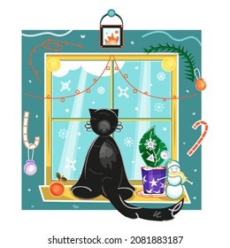A black cat sitting near window at winter day, a New Year card imaging a cat on windowsill, a window with Christmas tree branch, New Year toys, snowman, flower pot, garlands, candlestick, mandarin.