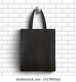 Black fabric tote bag hanging on white brick wall - realistic branding mockup of reusable shopping handbag for company merchandise design, vector illustration.