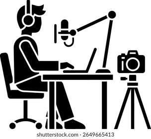 Black Filled Icon of Person at Desk with Microphone, Laptop, and Camera