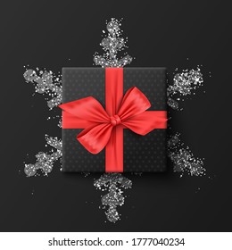 Black gift box. On a silver snowflake. On a dark background