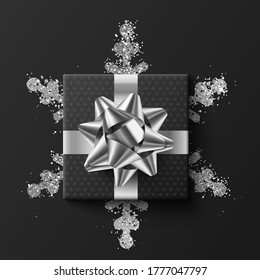 Black gift box. On a silver snowflake. On a dark background. Vector illustration