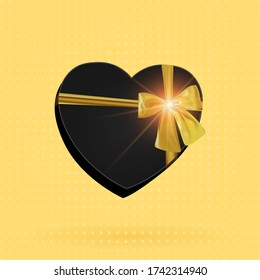 Black gift box in the shape of a heart with a luminous golden bow. Gift on a yellow vintage background