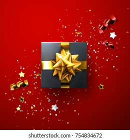 Black gift box with shiny golden bow and ribbons with sparkling confetti and tinsel particles on red background. Vector realistic festive illustration. Decoration element for design. Sale season