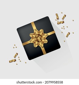 Black gift box with shiny yellow ribbon, bow and confetti particles.