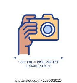 Black hand with camera pixel perfect RGB color icon. Person taking shot with analog equipment. Photographer tool. Isolated vector illustration. Simple filled line drawing. Editable stroke