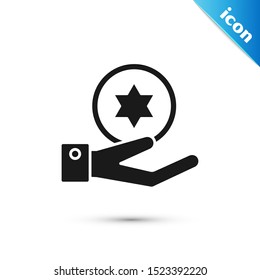 Black Jewish coin on hand icon isolated on white background. Currency symbol.  Vector Illustration