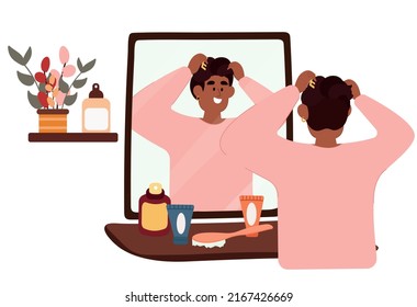 A black man stands in front of a mirror and does his hair. Daily morning routine of a man.