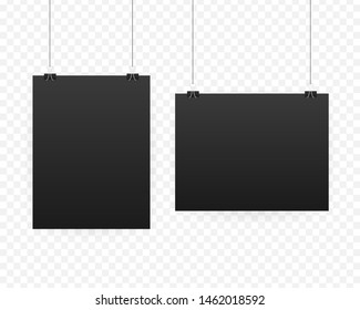 Black poster hanging on binder clips. Grey wall with mock up empty paper blank. Layout mockup. Vertical template sheet