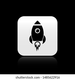 Black Rocket ship with fire icon isolated on black background. Space travel. Silver square button. Vector Illustration