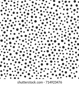 Black round spots scattered on white background. Seamless pattern. Irregular polka dot. Drawn by hand. Vector illustration.