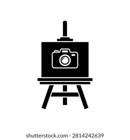 Black silhouette of a camera placed on an artist easel for display