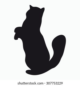 Black silhouette of a large adult cat isolated on a light background. Cat standing on his hind legs and reaches up.
