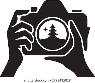 Black silhouette of two hands holding a camera with a tree and star inside the lens view finder de