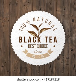 Etiqueta de papel redondo del té negro sobre fondo de madera