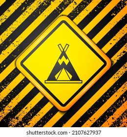 Black Traditional indian teepee or wigwam icon isolated on yellow background. Indian tent. Warning sign. Vector
