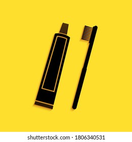 Tubo negro de pasta dental e ícono de cepillo de dientes aislado en fondo amarillo. Estilo de sombra larga. Vector.