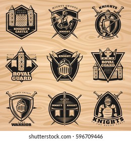 Black vintage knights emblems set with medieval weapon shield  castle and tower on wooden background isolated vector illustration