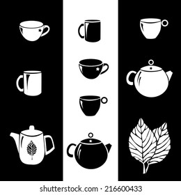 Black and white cups and kettles (teapots) with tea leaves on the background