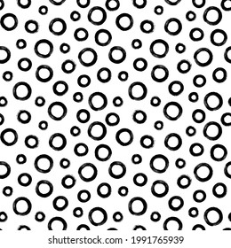 Black and white seamless pattern with rings in brush stroke technique. Vector abstract background with random hand painted circles.