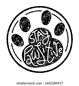 Black and white stamp of cat or dog paw print with Stay Pawsitive pun in hand-drawn lettering with vintage texture. Isolated on white background. Ready for screen print, laser cut, photo overlay.