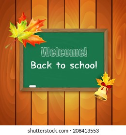 Blackboard decorated with autumn maple leaves on background a wooden wall