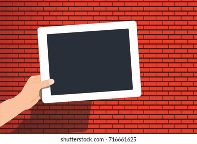 Blank digital tablet before red brick wall in hand
