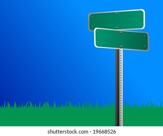 A blank green road/street sign is against a bright blue sky and grass is behind it.