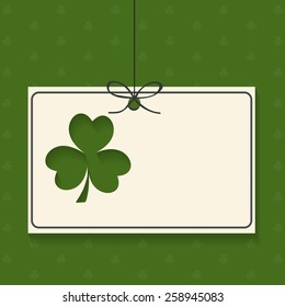 Blank hanging card with Irish lucky clover leaf on green background for Happy St. Patrick's Day celebration.