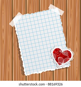 Blank notebook paper and small valentine on a wooden wall