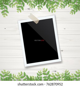 Blank photo frame or picture frame with framing of green leaves and wooden texture background. Realistic vector illustration.