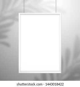 Blank white frame for a picture or poster hanging on strings. The shadow of the palm tree leaf falls on the wall behind.  Mockup with element for design