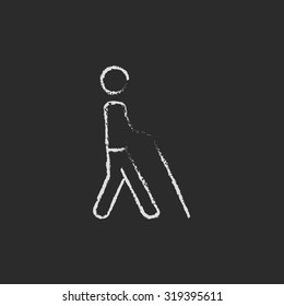 Blind man with stick hand drawn in chalk on a blackboard vector white icon isolated on a black background.