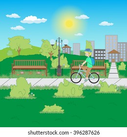 Blond boy goes through the park on a blue bicycle in a protective helmet with the backpack on the background of the city
