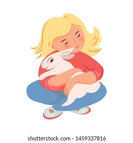 Blonde girl in red sweater is hugging white rabbit