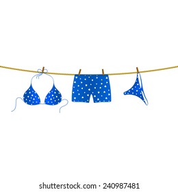 Blue Bikini Suit With White Dots And Boxer Shorts With White Hearts Hanging On Rope