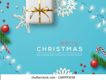 Blue Christmas background with Christmas decor including lights, baubles, gift box, fir tree cuttings, glitter, berries and candy vane. Vector Illustration.