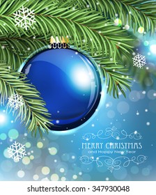 Blue Christmas ball and fir tree branches on a sparkling  holiday background. Festive Christmas background