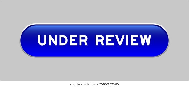 Blue color capsule shape button with word under review on gray background