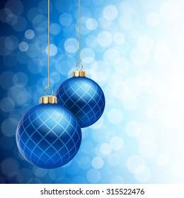 A Blue defocused Christmas background, with two blue striped christmas balls decorated with snowflakes, hanging from above.