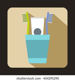 Blue plastic cup with brushes icon in flat style on a beige background