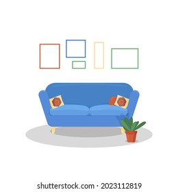 blue sofa next to a flower in a pot and frames on the walls