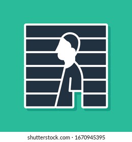Blue Suspect criminal icon isolated on green background. The criminal in prison, suspected near the board.  Vector Illustration