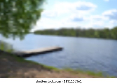 blurred background of a summer landscape with a small river, trees