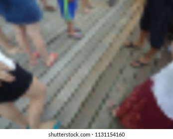 Blurred background of a wooden floor with legs in the slaps of different people who stood in a circle