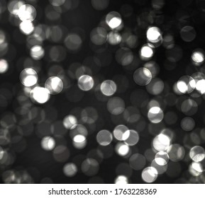 Blurred bokeh light on black background. Christmas and New Year holidays template. Abstract silver glitter defocused blinking stars and sparks. Vector EPS 10