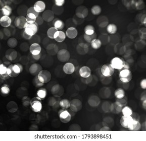 Blurred bokeh light on black background. Christmas and New Year holidays template. Abstract silver glitter defocused blinking stars and sparks. Vector EPS 10