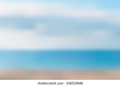 Blurred sandy summer beach with blue sea on background. Vacation travel wallpaper backdrop.