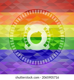 icono de bomba dentro del emblema sobre fondo de mosaico con los colores de la bandera LGBT. 