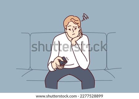Bored man holding TV remote due to lack of satellite TV channels with interesting shows. Concept frustration and procrastination associated with lack of motivation caused by emotional burnout 