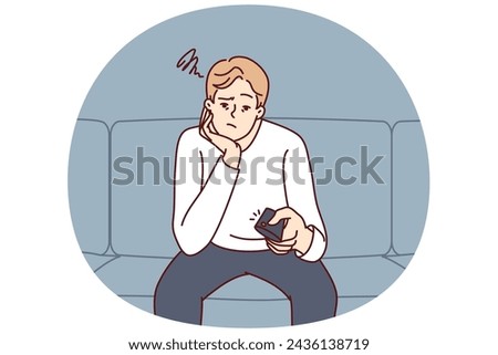 Bored man holding TV remote due to lack of satellite TV channels with interesting shows. Concept frustration and procrastination associated with lack of motivation caused by emotional burnout